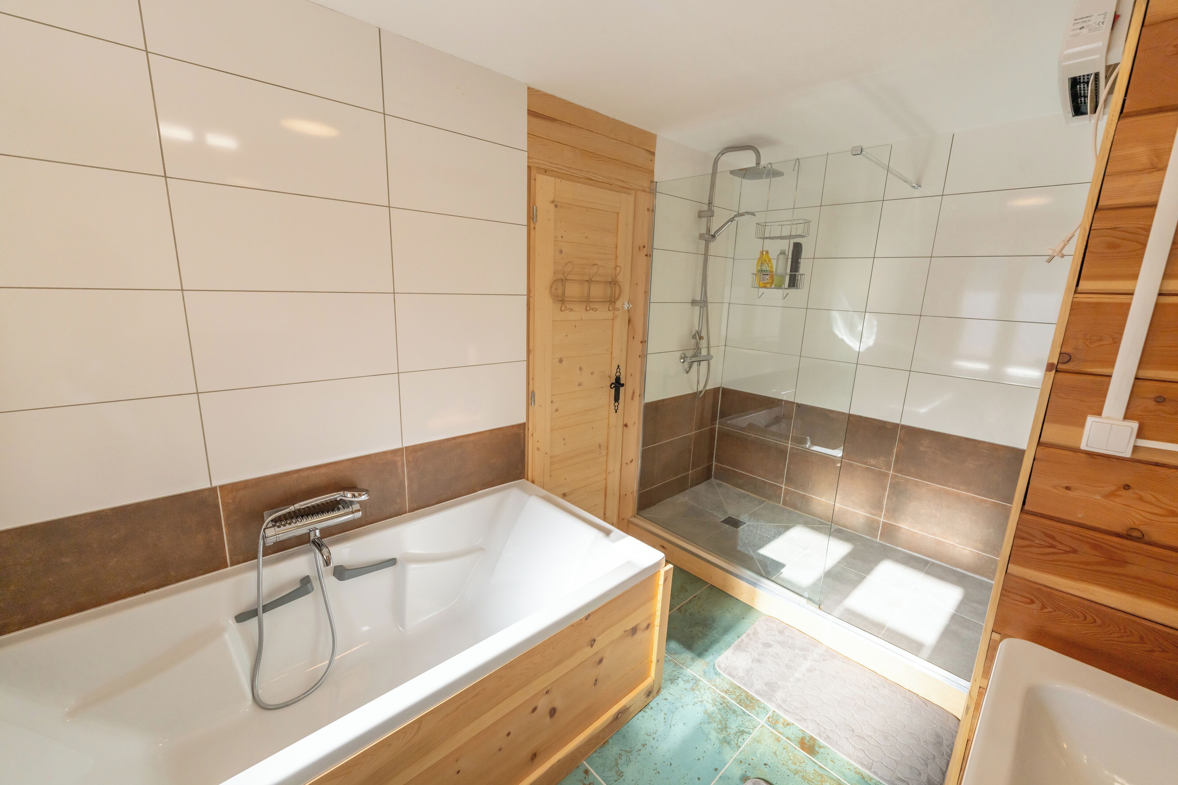 Een badkamer met een houten badkuip, een glazen douchecabine en een betegelde vloer.