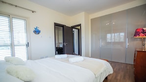 Een slaapkamer met een groot bed, een kledingkast en een badkamer die door een open deur zichtbaar is.