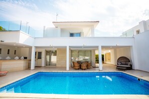 A modern house with a swimming pool, a dining area with outdoor furniture, and a covered patio. - Beachfront 3 BDR Villa With Pool (Pyla)