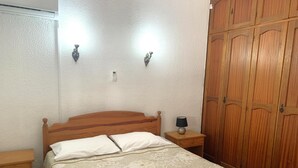 Ein Schlafzimmer mit einem Holzbett, zwei Nachttischen, einem Nachttisch, einem Holzschrank und zwei Wandleuchten.