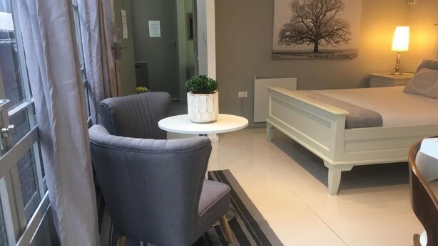 Une chambre à coucher moderne avec un lit, une chaise, une petite table avec une plante et un tableau au mur.