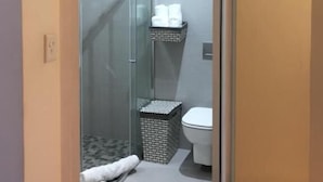 A compact bathroom with a glass shower enclosure, a toilet, and a towel rack. - Man And Tree House  (Cape Town)