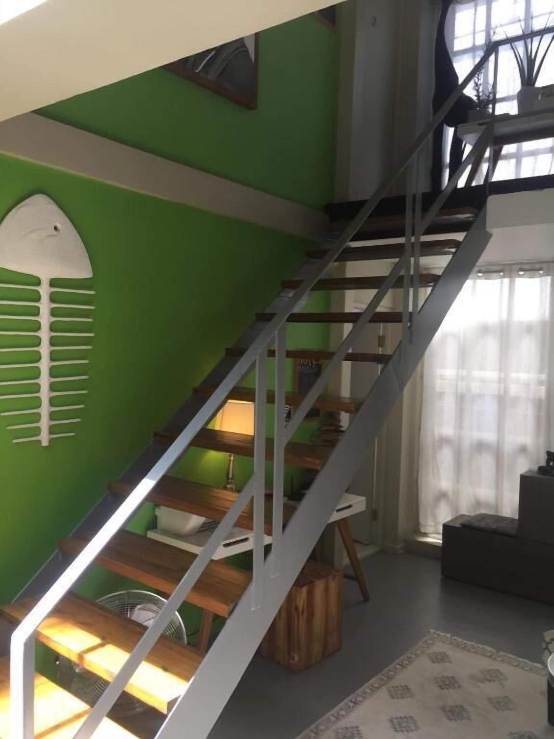 Una escalera de madera con barandales de metal que conduce a un piso superior.