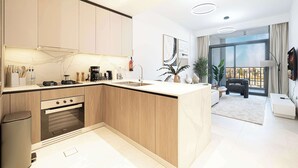 A modern kitchen with a built-in oven, a sink, and a dining area with a sofa and a plant. - Modern 1-Bedroom Apartment With Padel Court Access (Arjan)