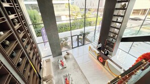 A modern hotel lobby with a marble floor, a reception desk, and a view of the street through large windows. - Modern 1-Bedroom Apartment With Padel Court Access (Arjan)