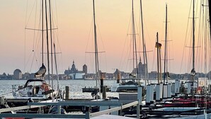 A marina with multiple sailboats docked, a city skyline in the background, and a clear sky. - Living with a harbor view—200 meters from the South Beach on the island of Rügen (Altefähr)
