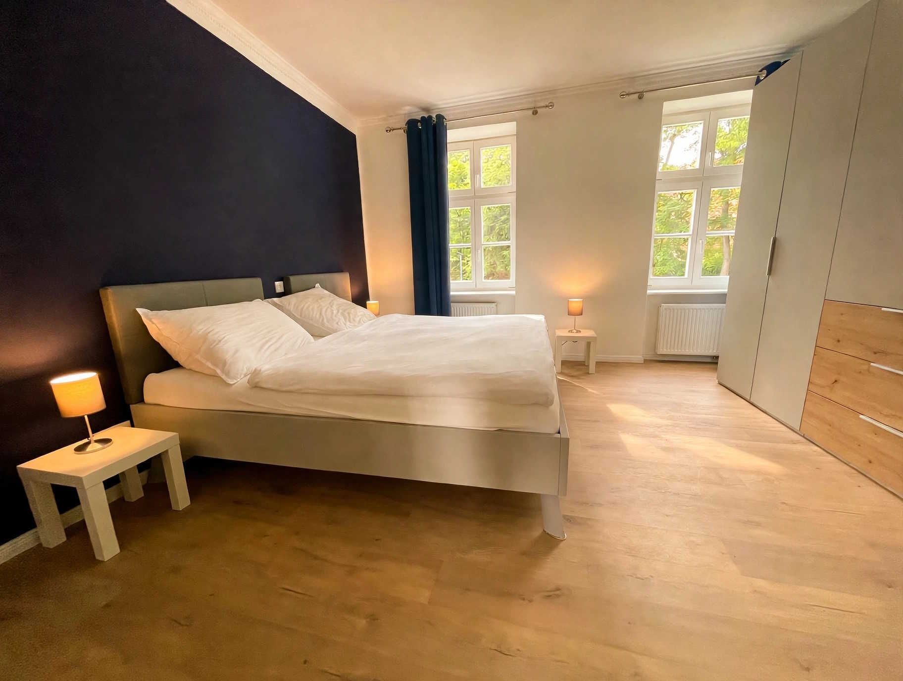 Une chambre à coucher avec un lit, des lampes de chevet, une fenêtre et une armoire.