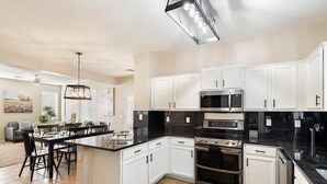 A modern kitchen with white cabinets, black countertops, and stainless steel appliances. - 4-bedroom, 3 Bath Home in Gilbert—Pets Welcome  (Gilbert)