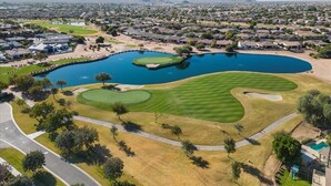 A golf course with a pond, surrounded by residential areas and mountains in the background. - 4-bedroom, 3 Bath Home in Gilbert—Pets Welcome  (Gilbert)