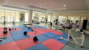 A spacious gym with various exercise equipment, including treadmills and weight machines, on red and blue mats.