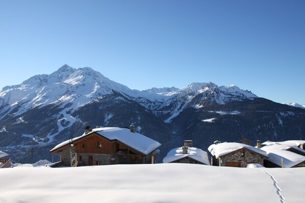 A mountain lodge with snow-covered roofs and a clear view of snow-capped peaks in the background. - Authentic CHALET 15 people "LA BERGERIE" - La Rosière 1850 (Montvalezan)