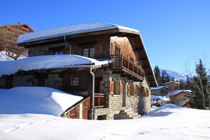 A wooden chalet with a stone base, a balcony, and a snow-covered roof. - Authentic CHALET 15 people "LA BERGERIE" - La Rosière 1850 (Montvalezan)