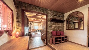 A cozy room with a stone wall, wooden furniture, and a wooden bench with cushions.