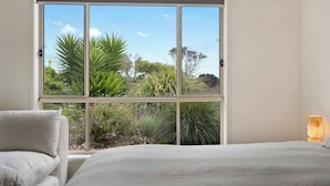 A bedroom with a large window, a bed, a chair, and a nightstand. - 15 Offshore Dr Middleton - Wi-Fi and Linen Included (Middleton)