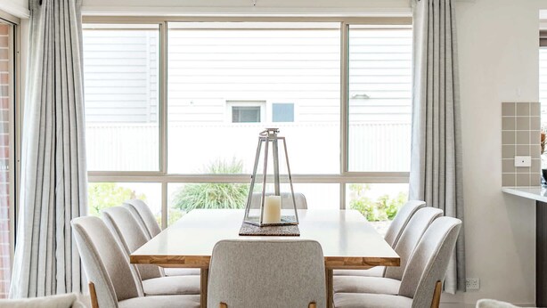 A dining area with a table and chairs, a candle, and a window with curtains. - 15 Offshore Dr Middleton - Wi-Fi and Linen Included (Middleton)