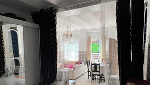 Amplia sala de estar con un espejo grande, una araña de cristal y vista al comedor.
