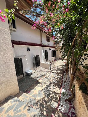 Un petit pati amb un edifici blanc, amb portals arquejats i un paviment de rajoles.