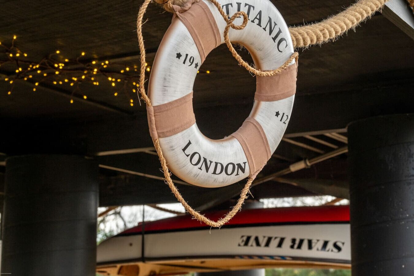 A lifebuoy with "TITANIC" and "LONDON" written on it, hanging from a rope.