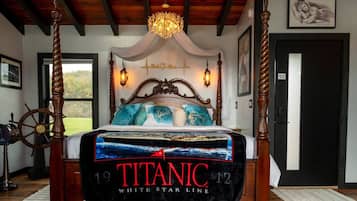 Una cama con dosel, un edredón con temática del Titanic, un candelabro y vistas al exterior.