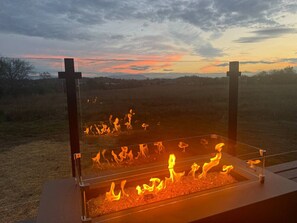 A fire pit with flames, set against a sunset sky.