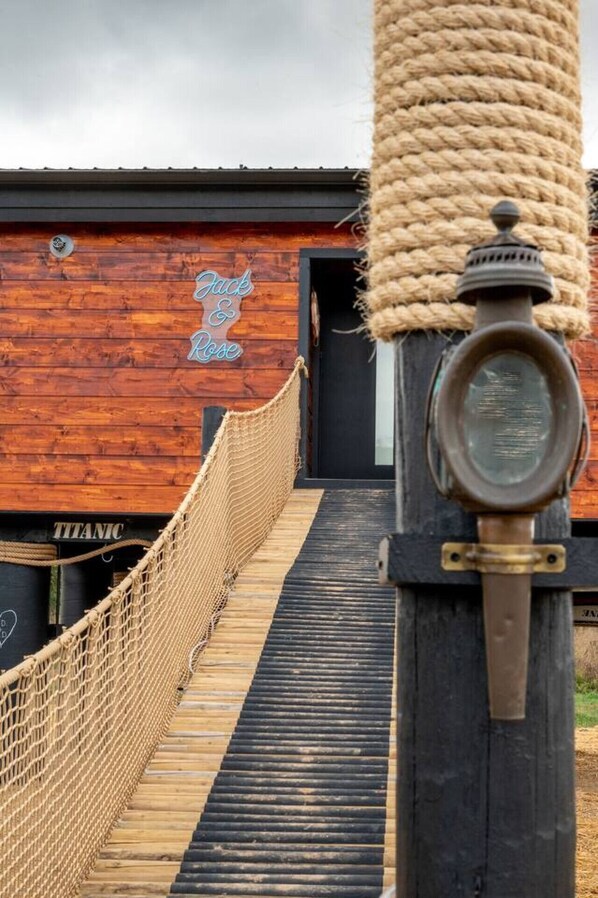 Una terraza de madera que conduce a un edificio con una barandilla de cuerda y un letrero que dice "Jack & Rose".