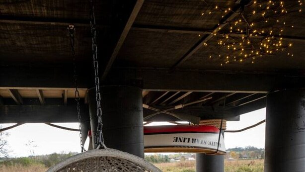 Un fauteuil suspendu, placé sous une structure d’où l’on peut admirer le paysage.