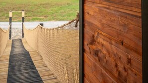 Un intérieur en bois, avec une bouée de sauvetage accrochée au mur et une vue sur un champ verdoyant, visible à travers une porte en bois.
