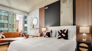 A modern hotel room with a large bed, a sofa, a small table, and a nightstand with a lamp. - Boulevard Stays Downtown Highrise STU Sky Pool, Parking, Gym 03 (Phoenix)