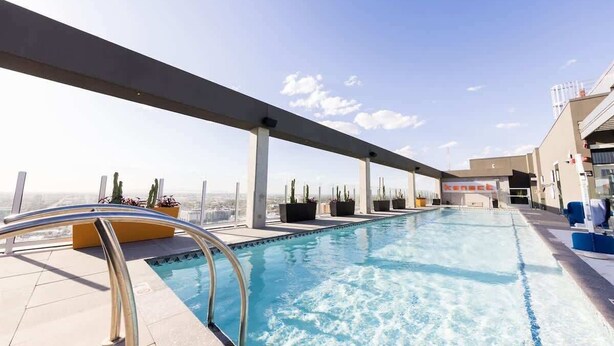 A rooftop pool with clear blue water, metal railings, and potted plants. - Boulevard Stays Downtown Highrise STU Sky Pool, Parking, Gym 07 (Phoenix)