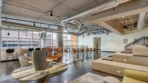A spacious indoor area with modern seating arrangements, large windows, and visible ductwork on the ceiling.
