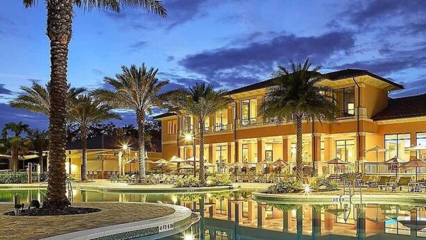 Un hôtel doté d’une piscine, de palmiers et d’un éclairage extérieur soigné, particulièrement agréable au crépuscule.