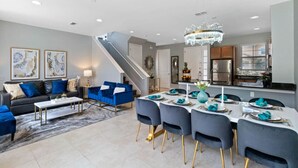 Un salon moderne comprenant un coin repas, un escalier et une cuisine.