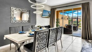 A modern dining area with a white table, black chairs, and a decorative mirror. - #2609 Resort Home near Disney Themed Jacuzzi Pool (Kissimmee)