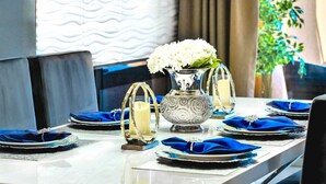 A dining table set with blue napkins, white plates, and a decorative silver bowl with a candle. - #2609 Resort Home near Disney Themed Jacuzzi Pool (Kissimmee)