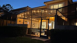 A house with a covered patio area, a visible door, and a small garden. - #2609 Resort Home near Disney Themed Jacuzzi Pool (Kissimmee)