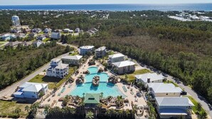 Luchtbeeld van een resort met meerdere gebouwen, een centraal gelegen zwembad en uitzicht op de oceaan.