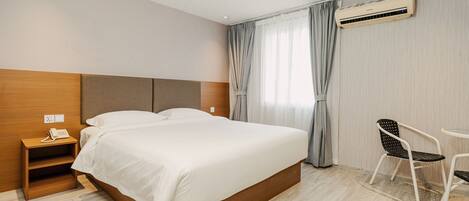 Una habitación de hotel con cama, mesita de noche, teléfono y una silla.