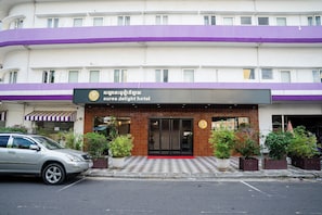 A hotel entrance with a checkered pavement, potted plants, and a parked car. - Aurea Delight Hotel (Phnom Penh)