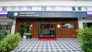 The exterior of the aurea delight hotel with a checkered floor, potted plants, and a red carpet entrance. - Aurea Delight Hotel (Phnom Penh)