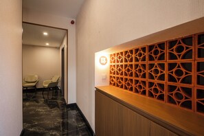 Un espace d’accueil doté d’un comptoir en bois, d’un mur orné de motifs et d’un coin salon avec des chaises.