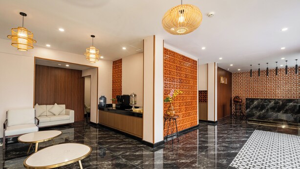 A modern lobby with a reception desk, seating area, and decorative wall panels. - Aurea Delight Hotel (Phnom Penh)