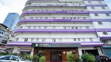 A multi-story hotel with a purple and white facade, a visible entrance, and a sign indicating it is the Aurea Delight Hotel.