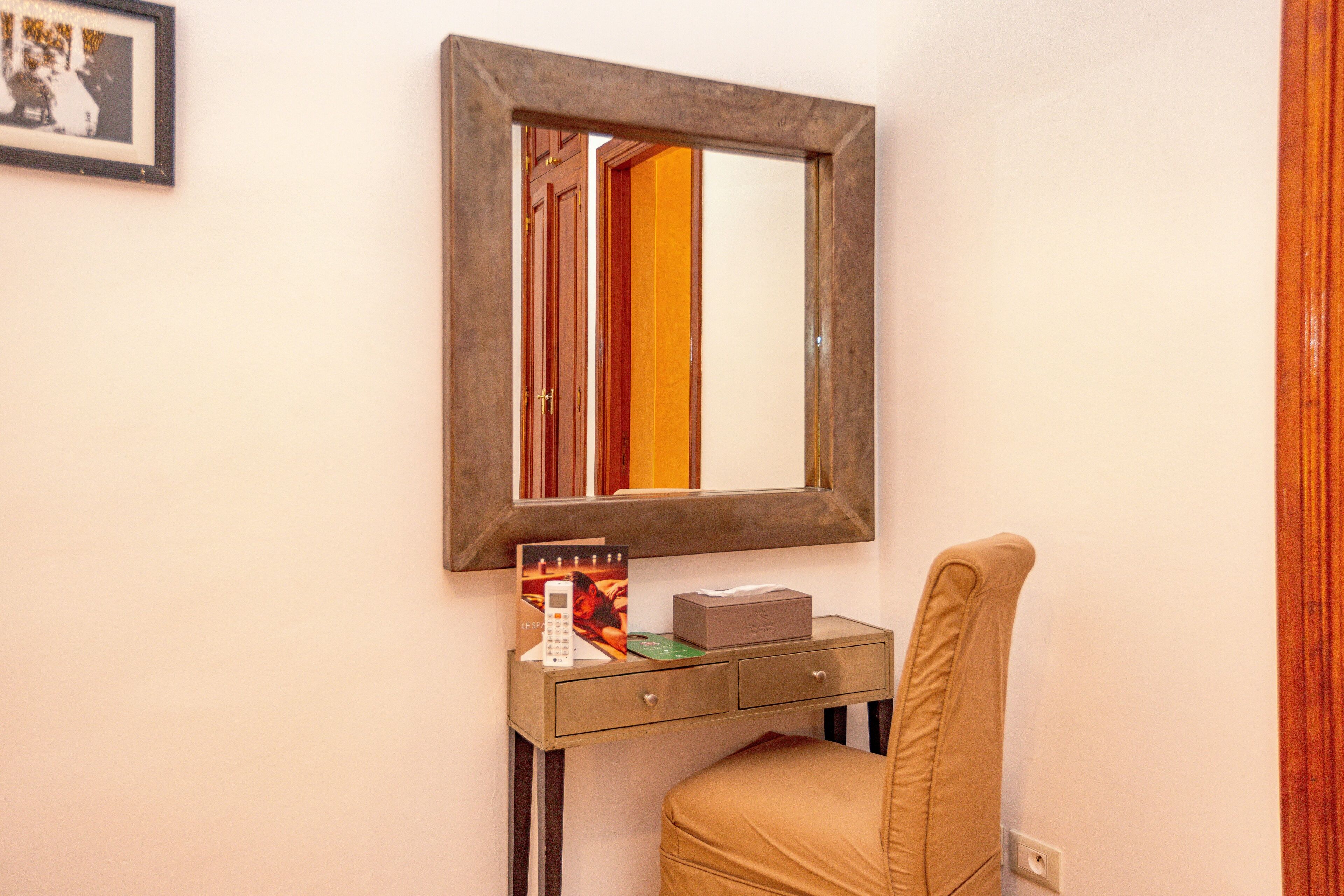Una habitación pequeña con un escritorio, una silla, un espejo y un cuadro en la pared.