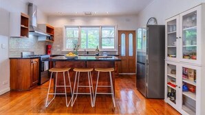 A modern kitchen with a central island, bar stools, a refrigerator, and a pantry. - Warburton Hideaway | MTB and Family Friendly (Warburton)