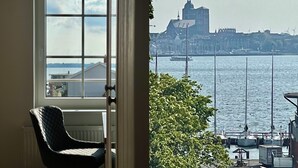 Een kamer met uitzicht op een haven, inclusief boten en een gebouw met een toren.