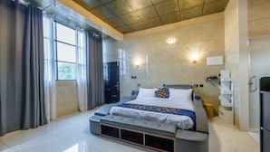 A modern hotel room with a large bed, built-in storage, a vanity, and a view of the outdoors. - W & H View Residency (Kochi)