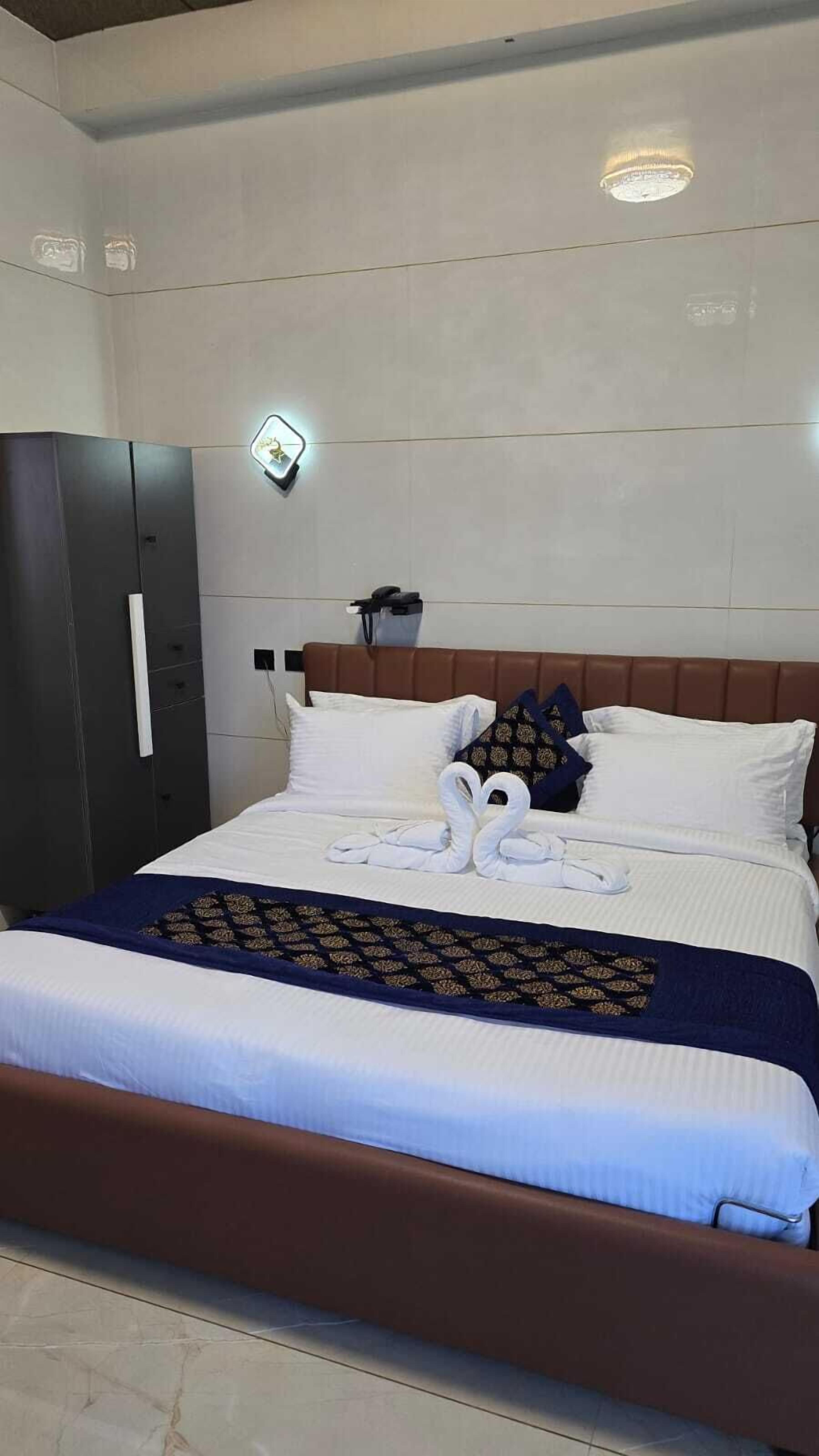 A neatly made bed with a brown headboard, white pillows, and a blue and gold patterned bedspread.