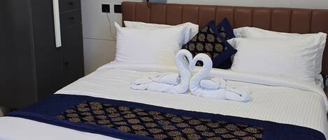 A neatly made bed with a brown headboard, white pillows, and a blue and gold patterned bedspread.