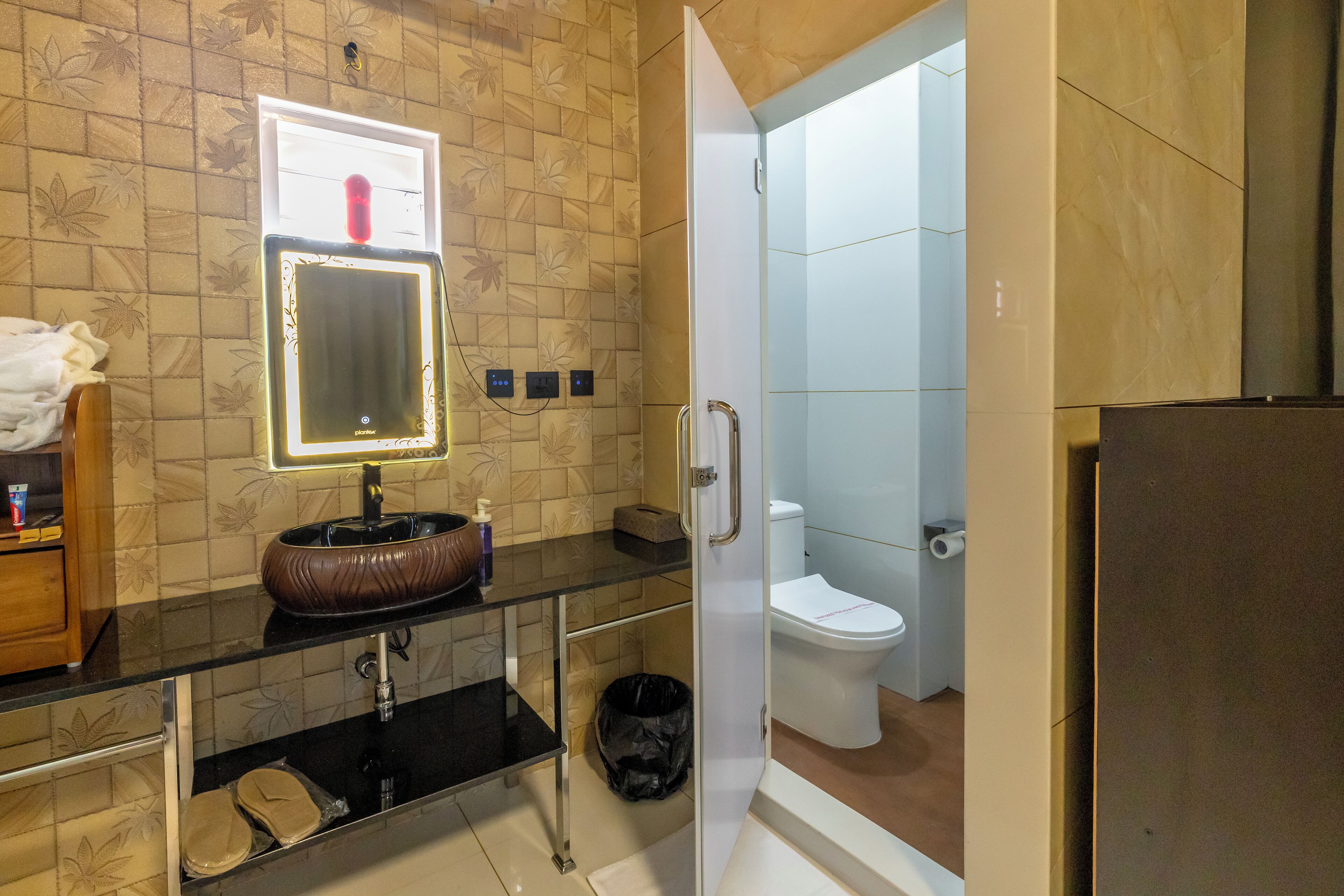 A bathroom with a glass sink, a mirror, a toilet, and a shower area.