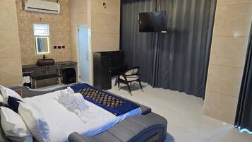 A hotel room with a bed, a desk, a chair, a TV, and a bathroom.